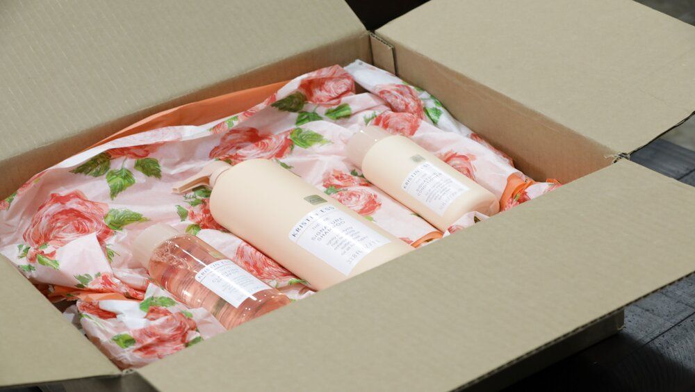 A cardboard box filled with bottles and wrapped in floral paper.