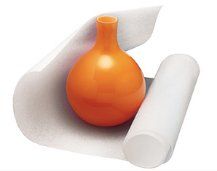 An orange vase is sitting on top of a roll of foam.