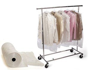 A roll of plastic bags is next to a clothes rack filled with clothes.
