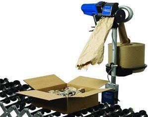A machine is packing a cardboard box with brown paper