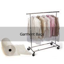 A roll of garment bags next to a clothes rack filled with clothes.