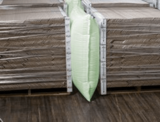 A green pillow is sitting on top of a stack of cardboard pallets.