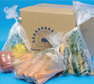 A box with vegetables in plastic bags next to it