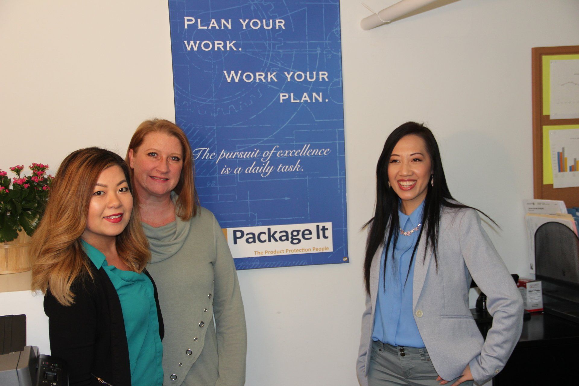 Three women are standing in front of a poster that says `` plan your work work your plan ''.