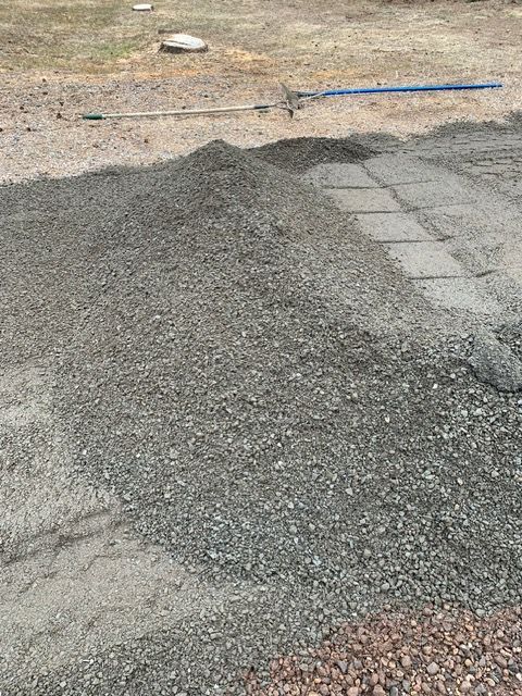 Pile of gravel next to a paved path on a construction site.