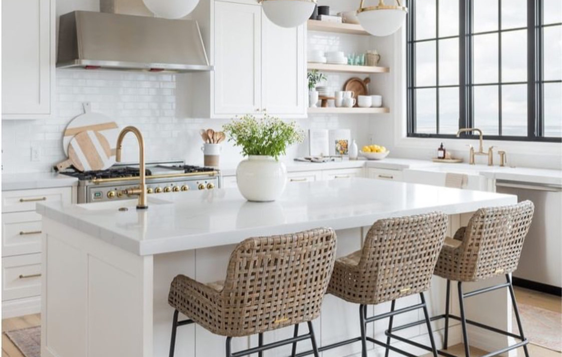 A kitchen with a large island and wicker bar stools.