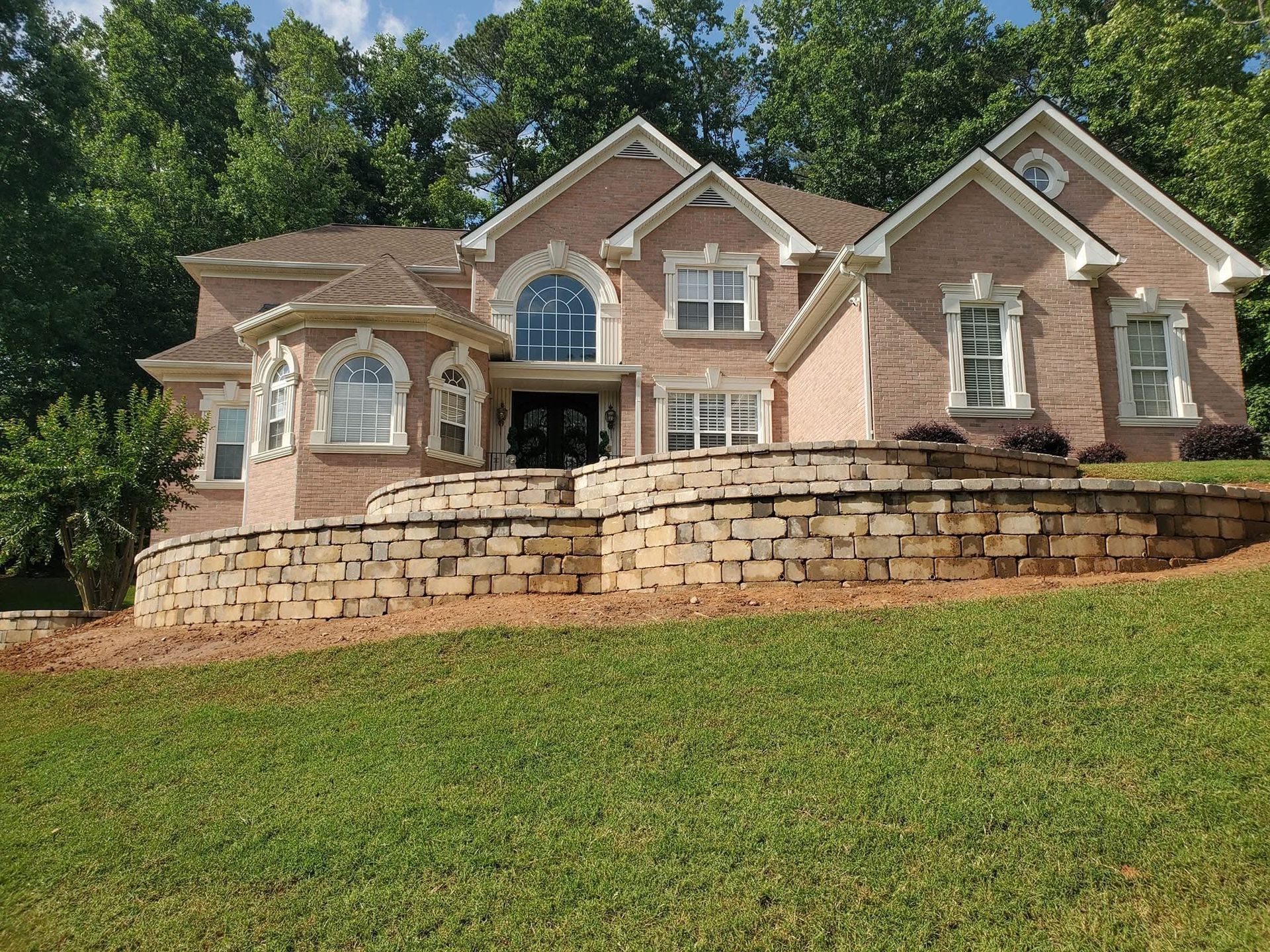 A large brick house with a stone wall in front of it