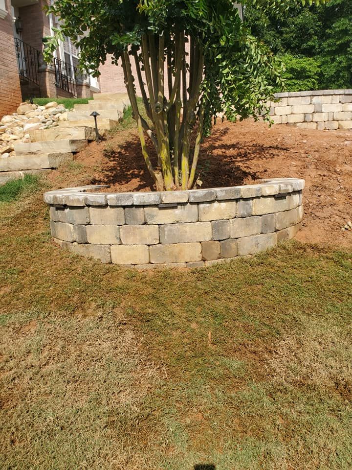 A large brick house with a stone wall in front of it