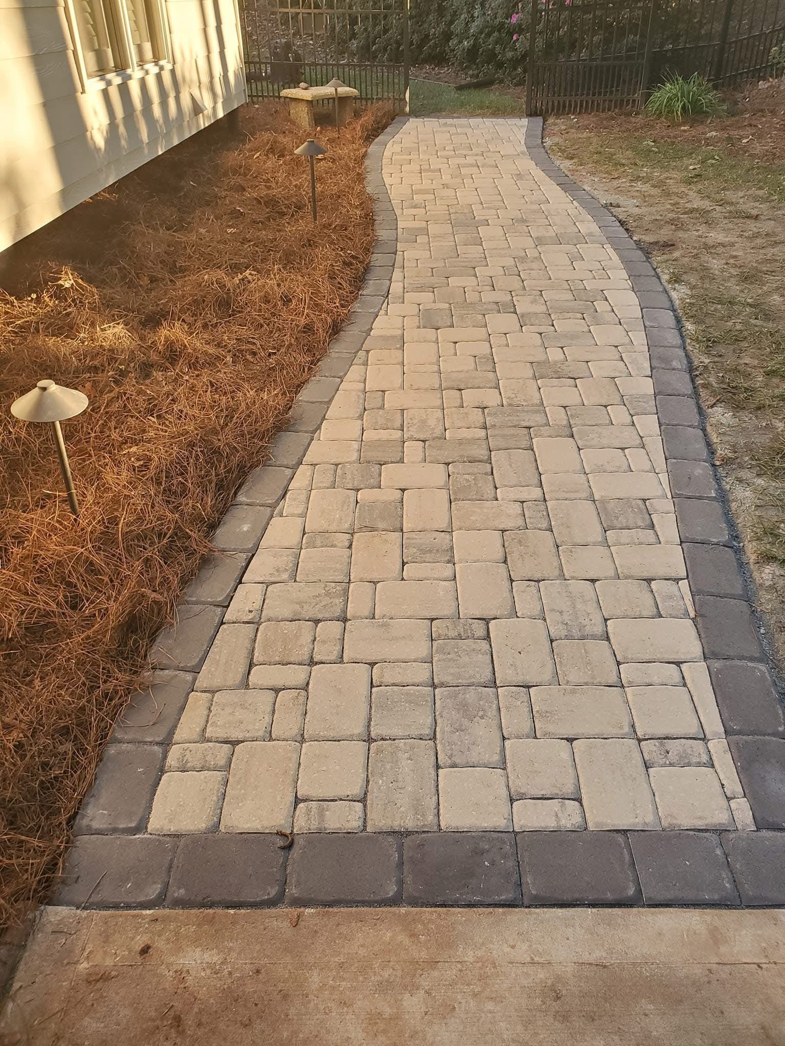 A walkway made of bricks is leading to a house.