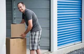 man holding box next to storage unit