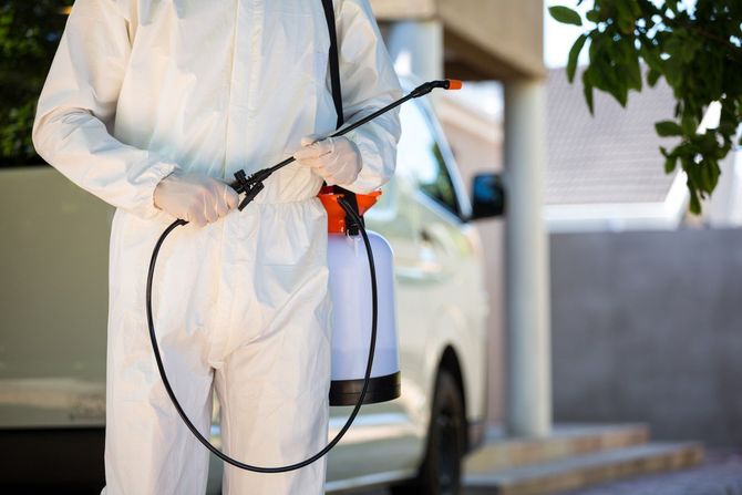 Exterminator in white protective suit holding spray nozzle
