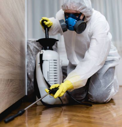 Exterminator in hazmat suit spraying kitchen floor for pests