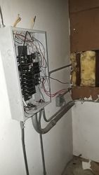 An electrical box is hanging on a wall in a room.