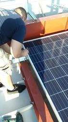 A man is working on a solar panel on top of a building.