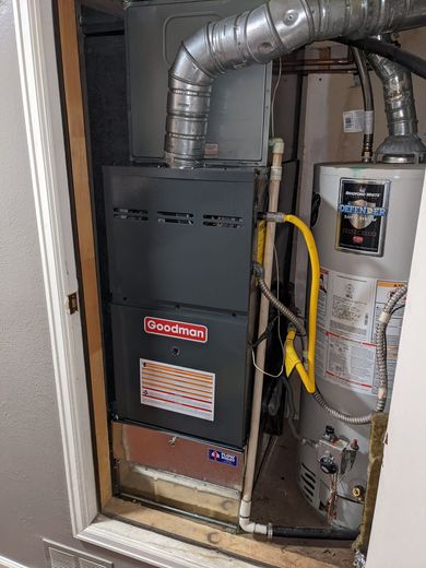 Furnace and water heater in a utility closet. Gray and silver appliances with vent pipes.