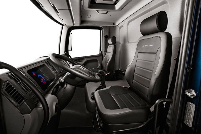 El interior de un camión con asientos negros y un volante.