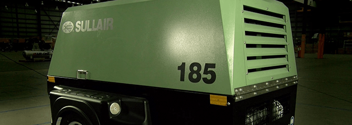 Un vehículo verde y negro con el número 185 en el costado está estacionado en una habitación oscura.