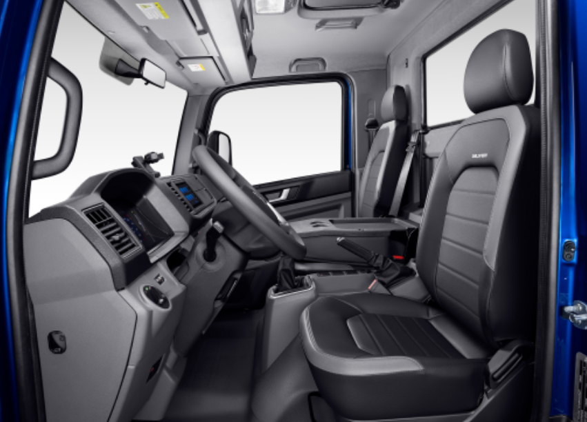 Interior de una cabina de camión azul con asientos, volante, tablero y ventanas de color gris y negro.