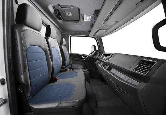 El interior de un camión con asientos azules y negros.