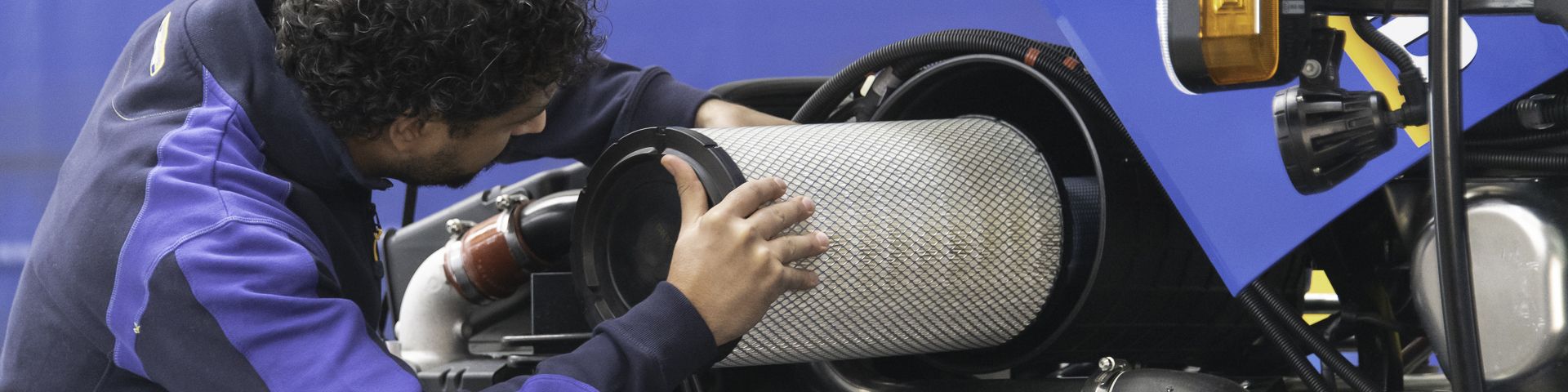 Un hombre con una chaqueta morada está trabajando en una motocicleta.