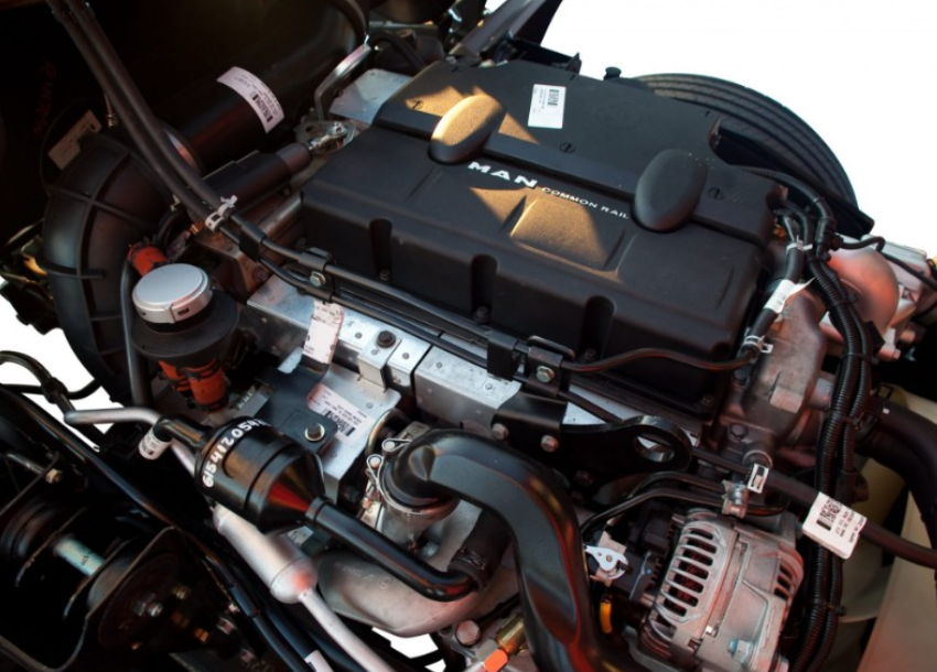Motor de camión, carcasa negra, con diversas mangueras y componentes visibles.