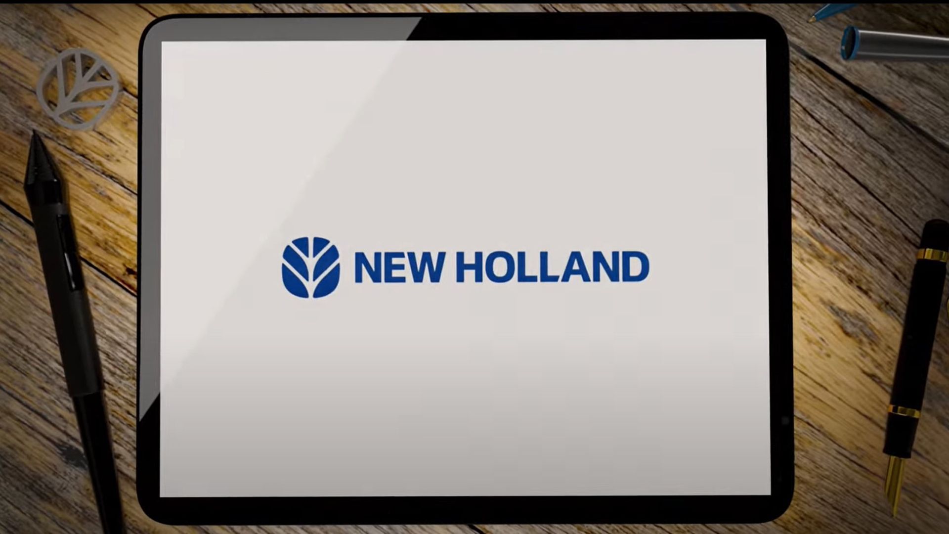 Una tableta con el logotipo de New Holland está sobre una mesa de madera.