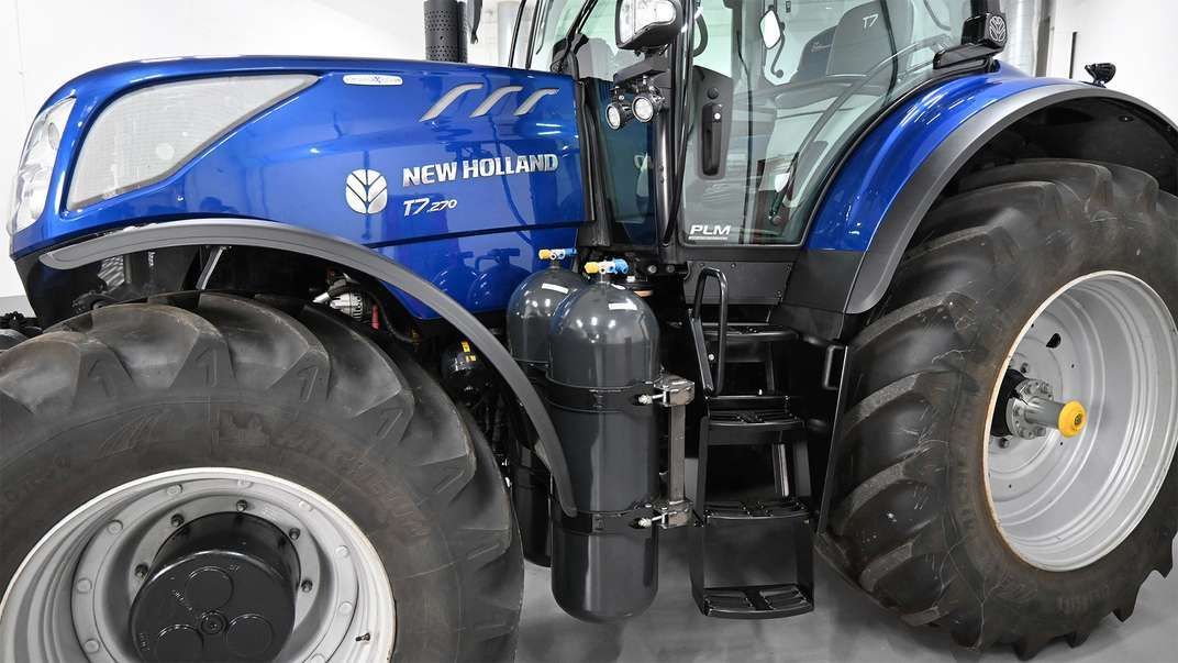 Un tractor agrícola new holland con neumáticos grandes está estacionado en un garaje.