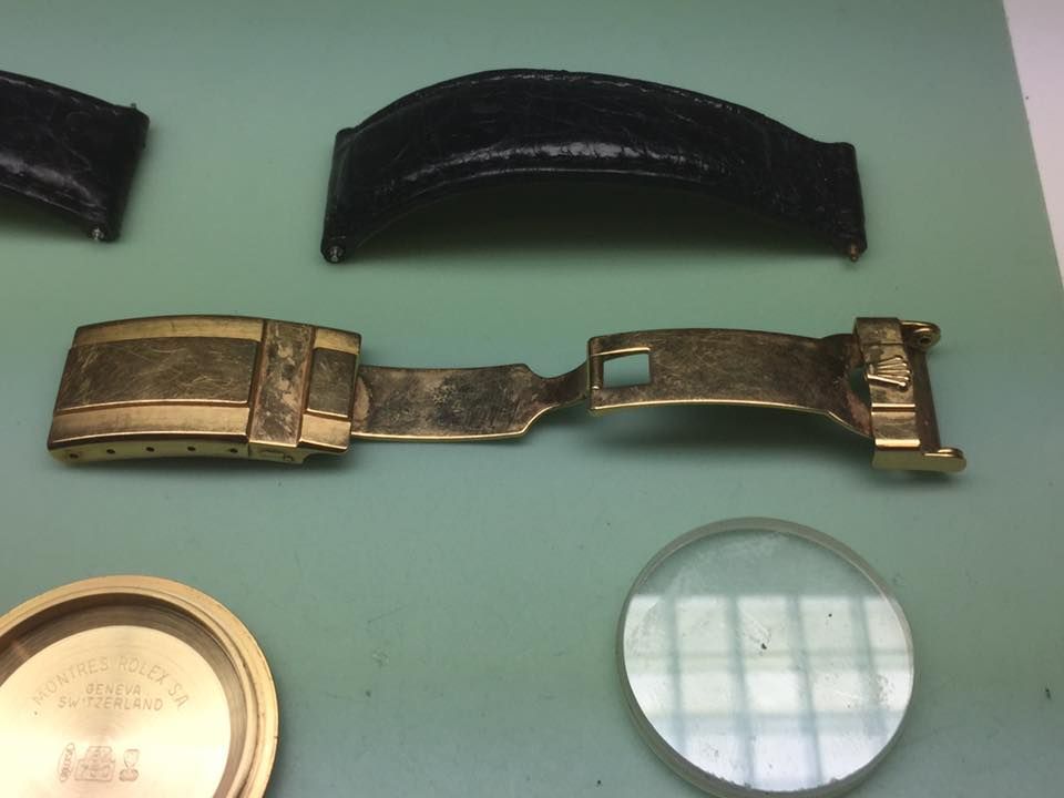 Primo piano di un orologio in riparazione su un tavolo verde.