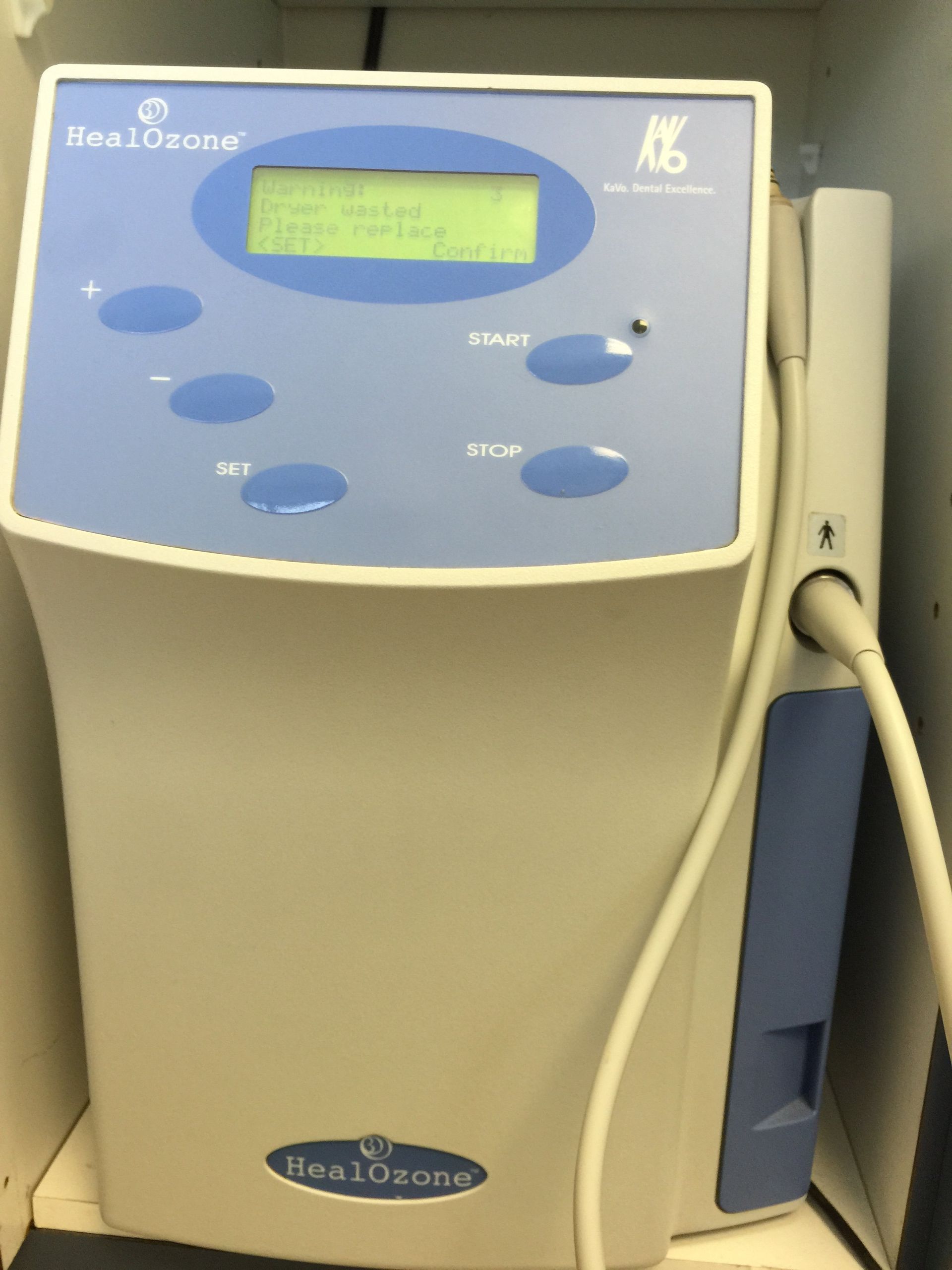 A beige HealOzone dental ozone therapy device with a blue control panel and a handpiece cable, resting on a flat surface.