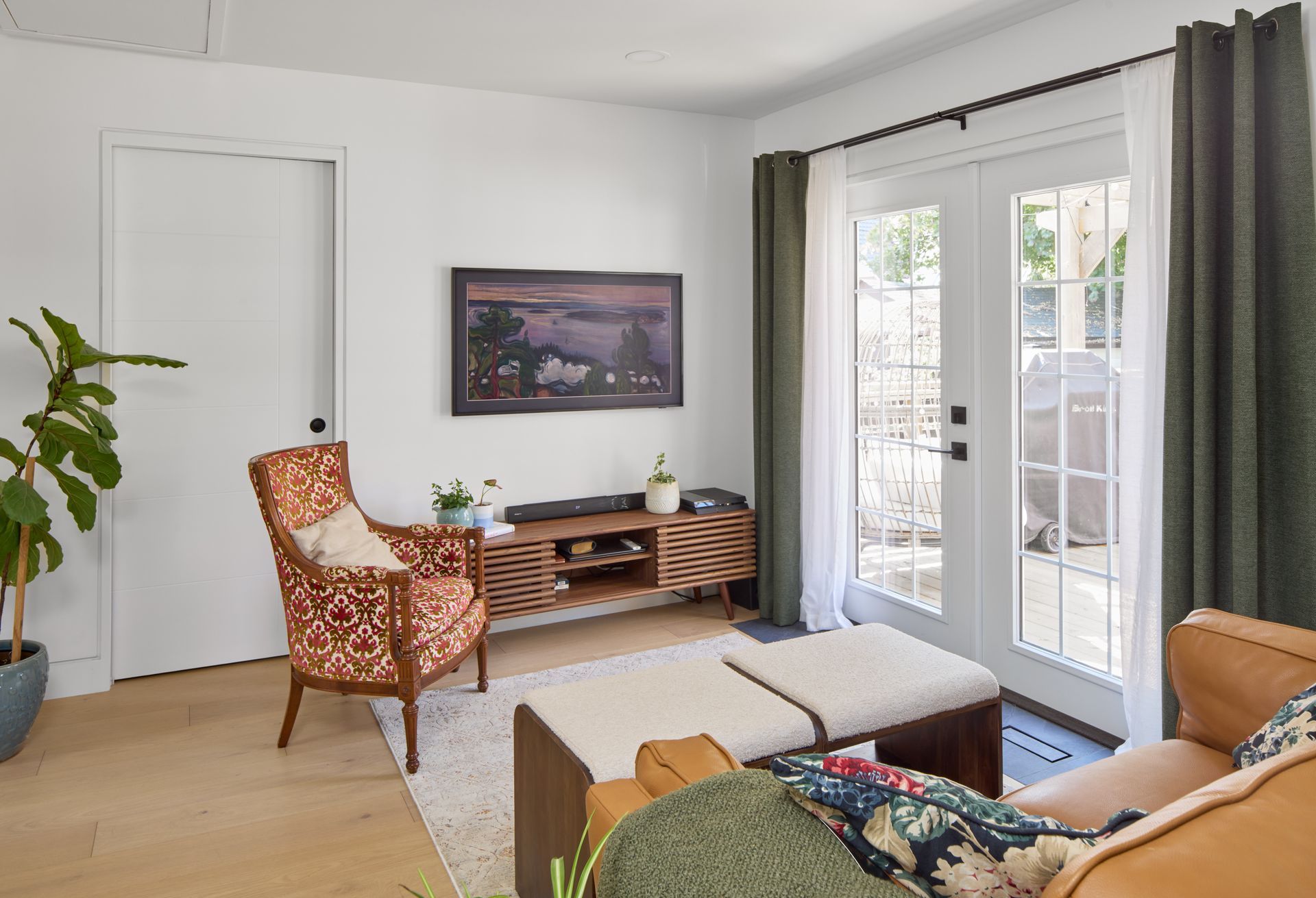 A living room with a couch , chair , ottoman and television.
