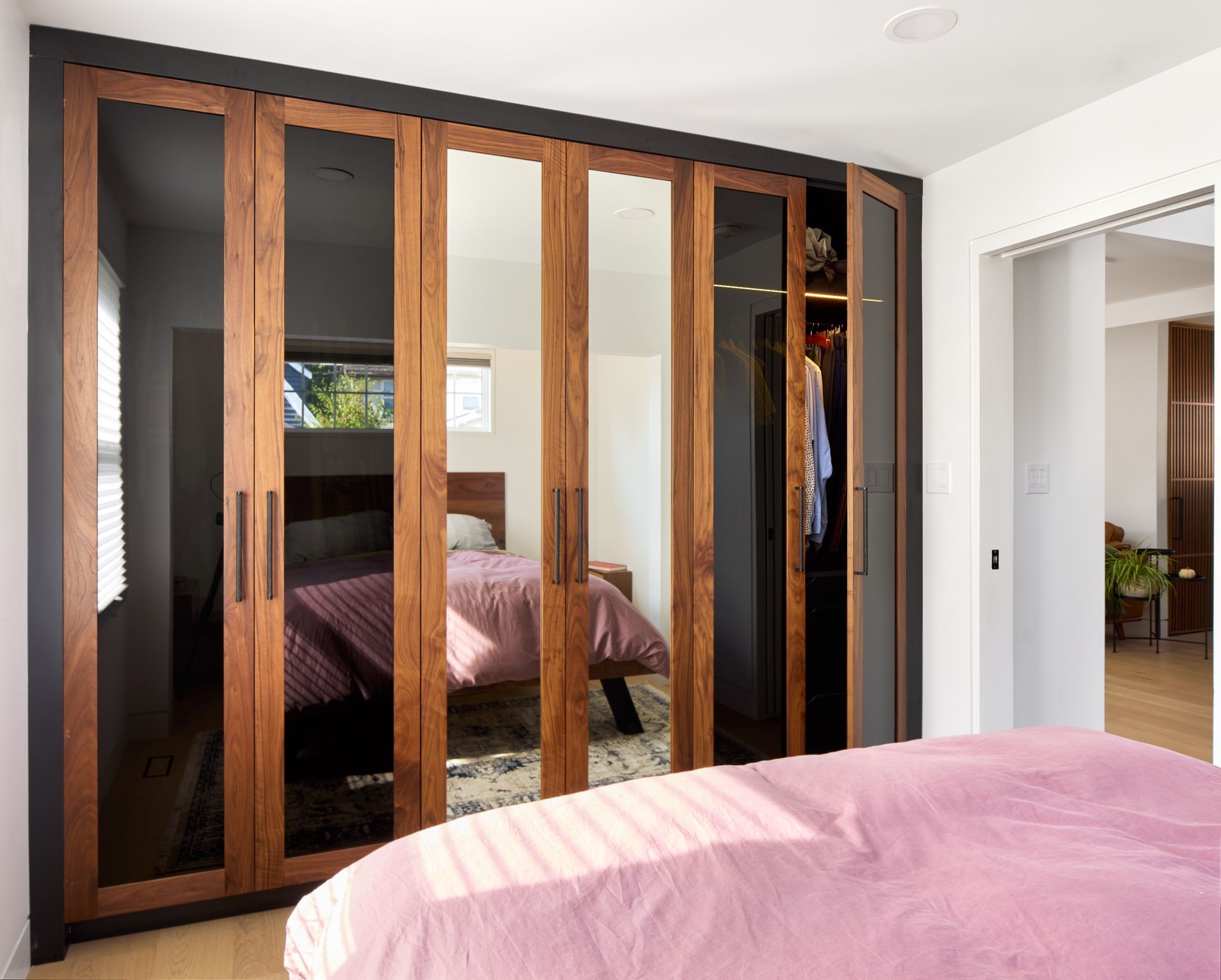 A bedroom with a bed , wardrobe , and mirrors.