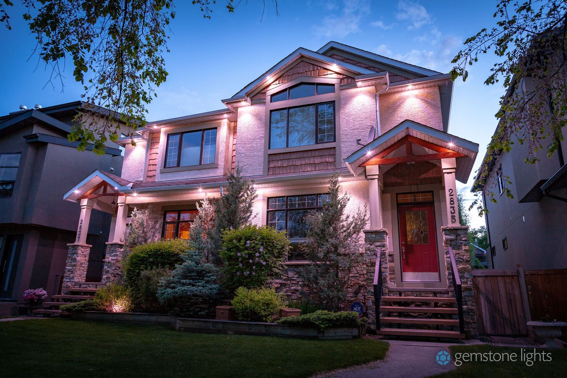 A large house with a red door is lit up at night