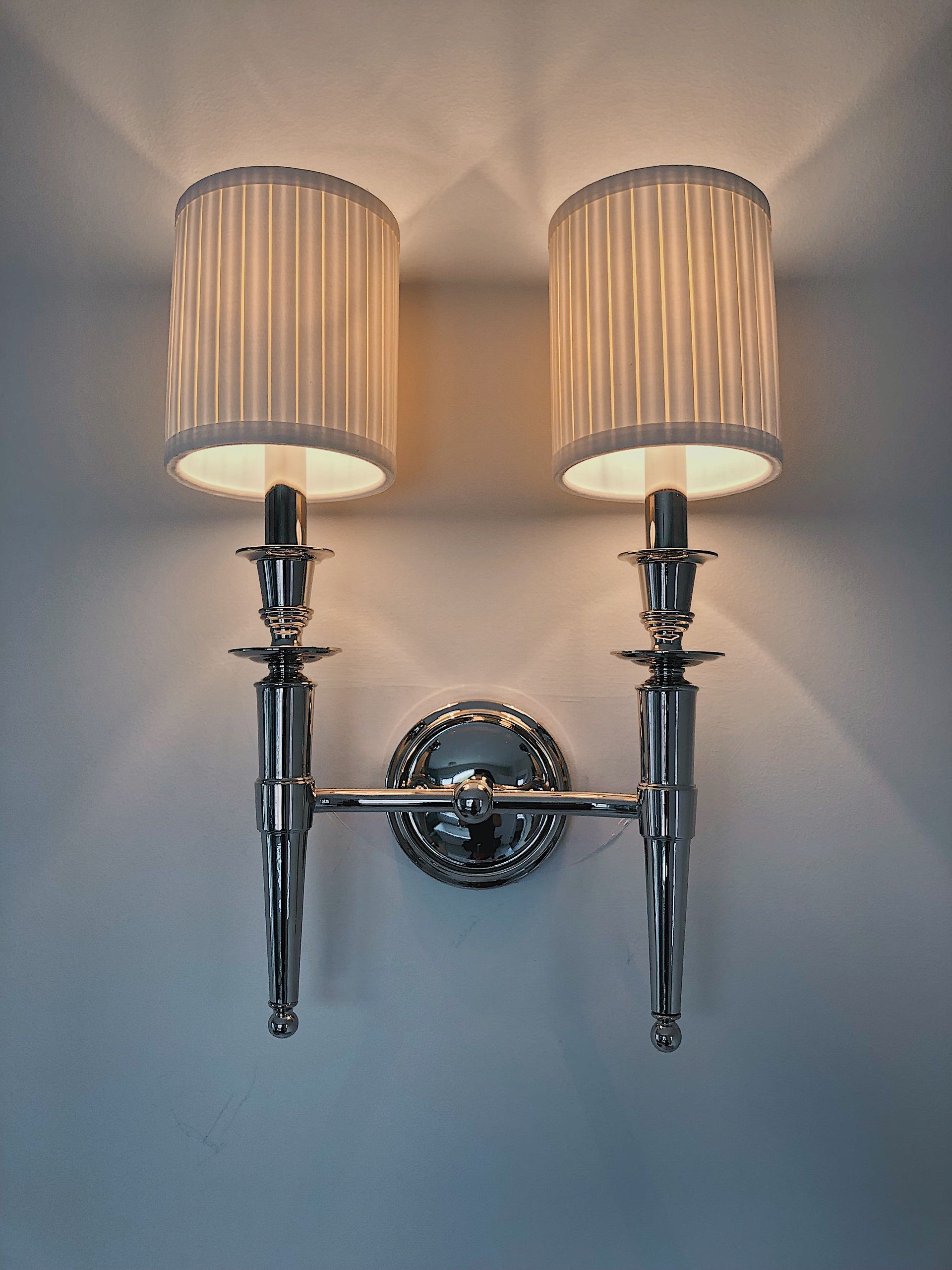 A pair of wall lights with shades on a wall.
