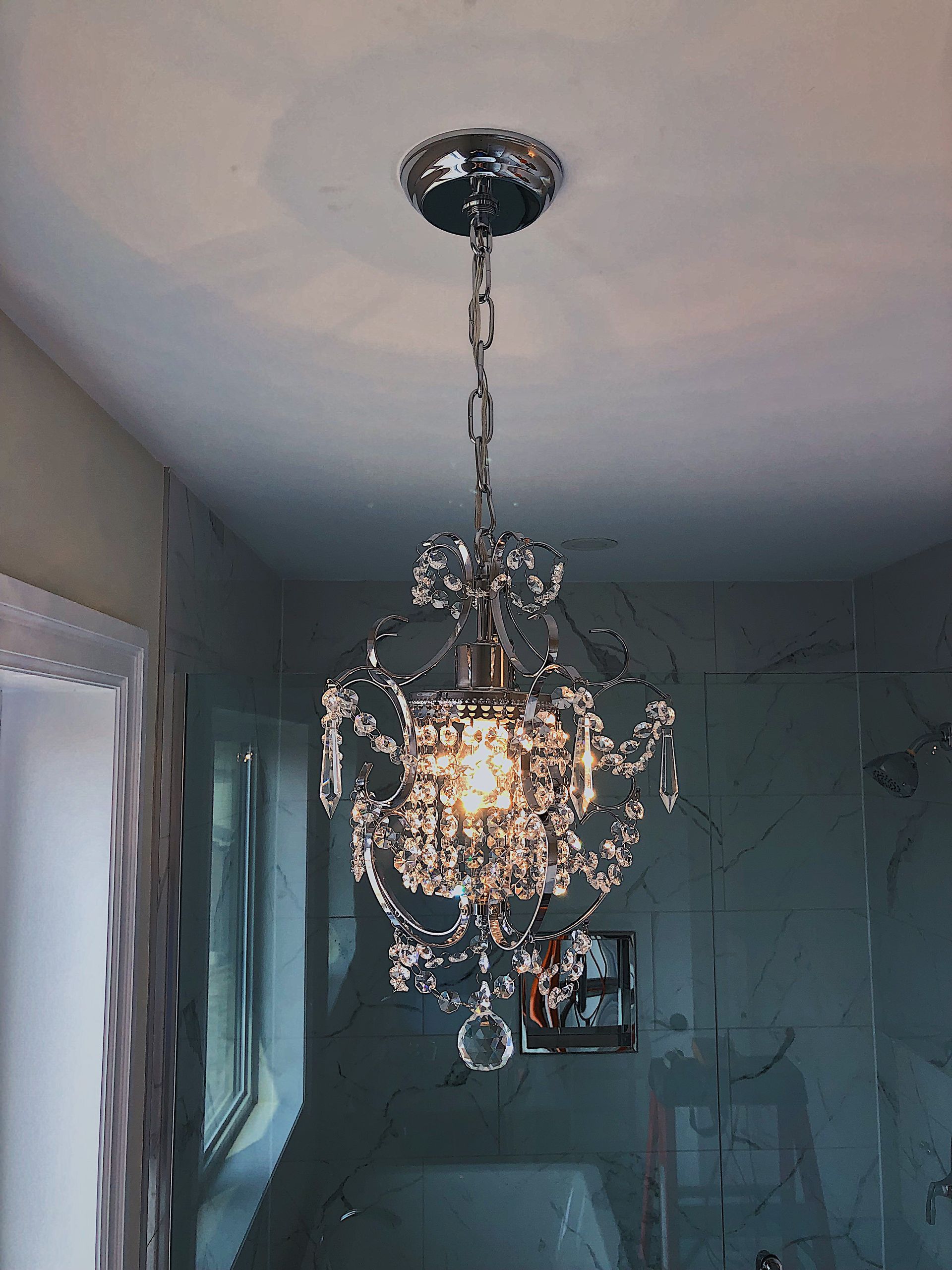 A chandelier is hanging from the ceiling in a bathroom.