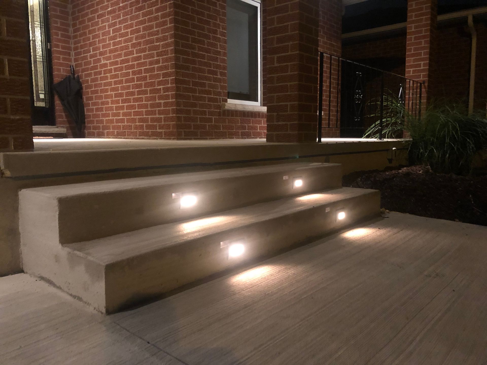 A brick house with stairs that are lit up at night.