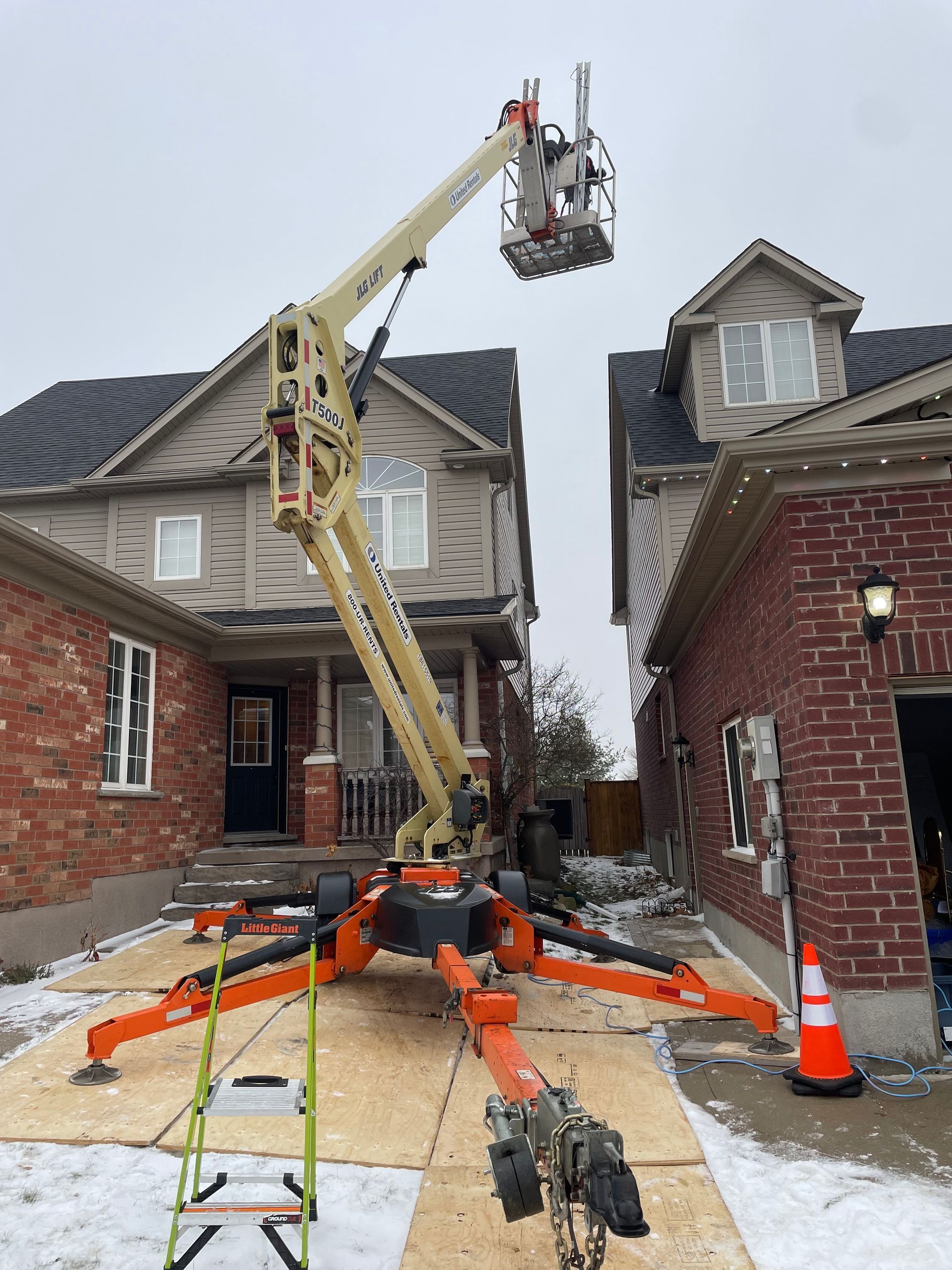 A crane is sitting in front of a brick house.