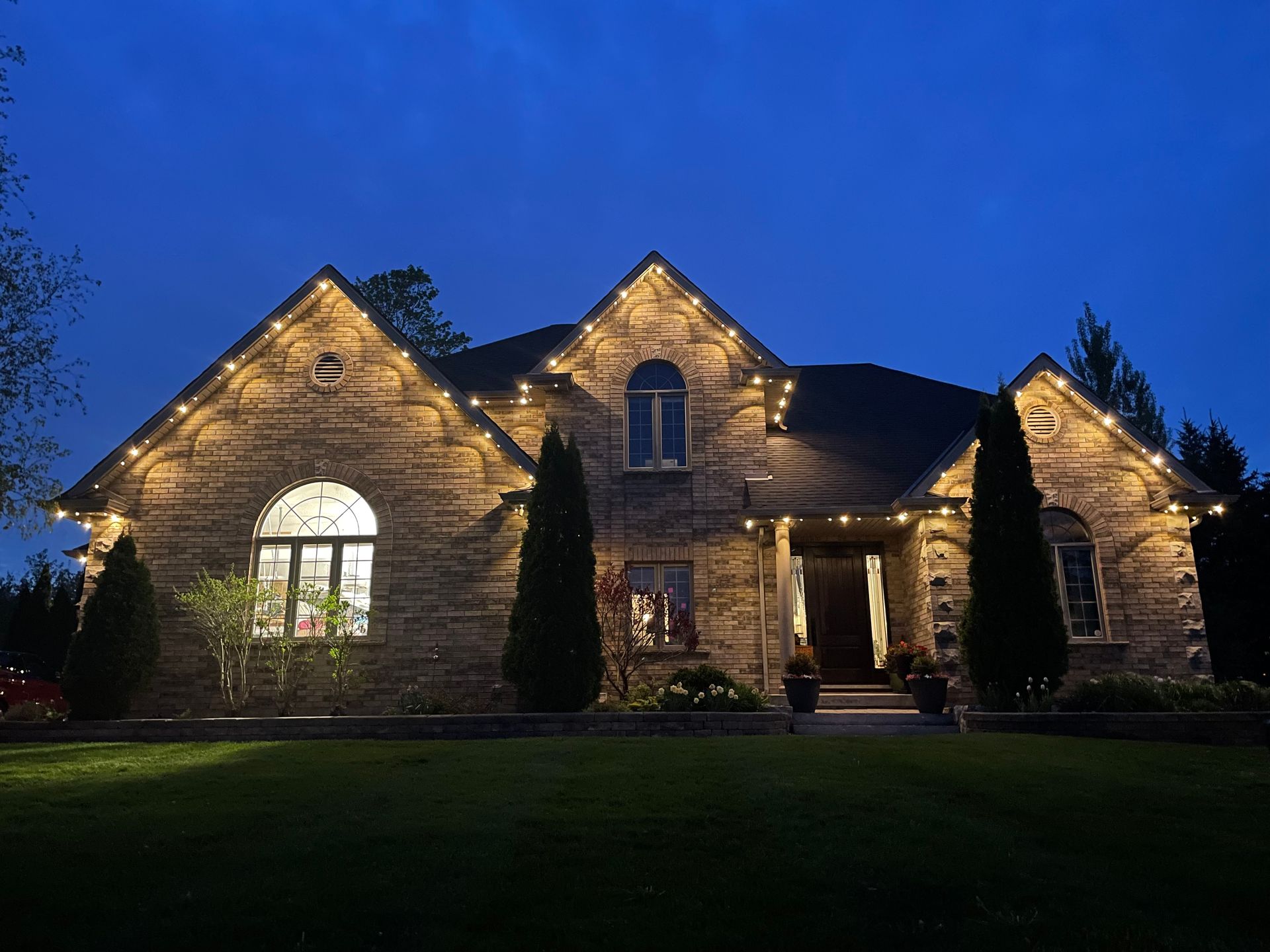 A large brick house is lit up at night with christmas lights.