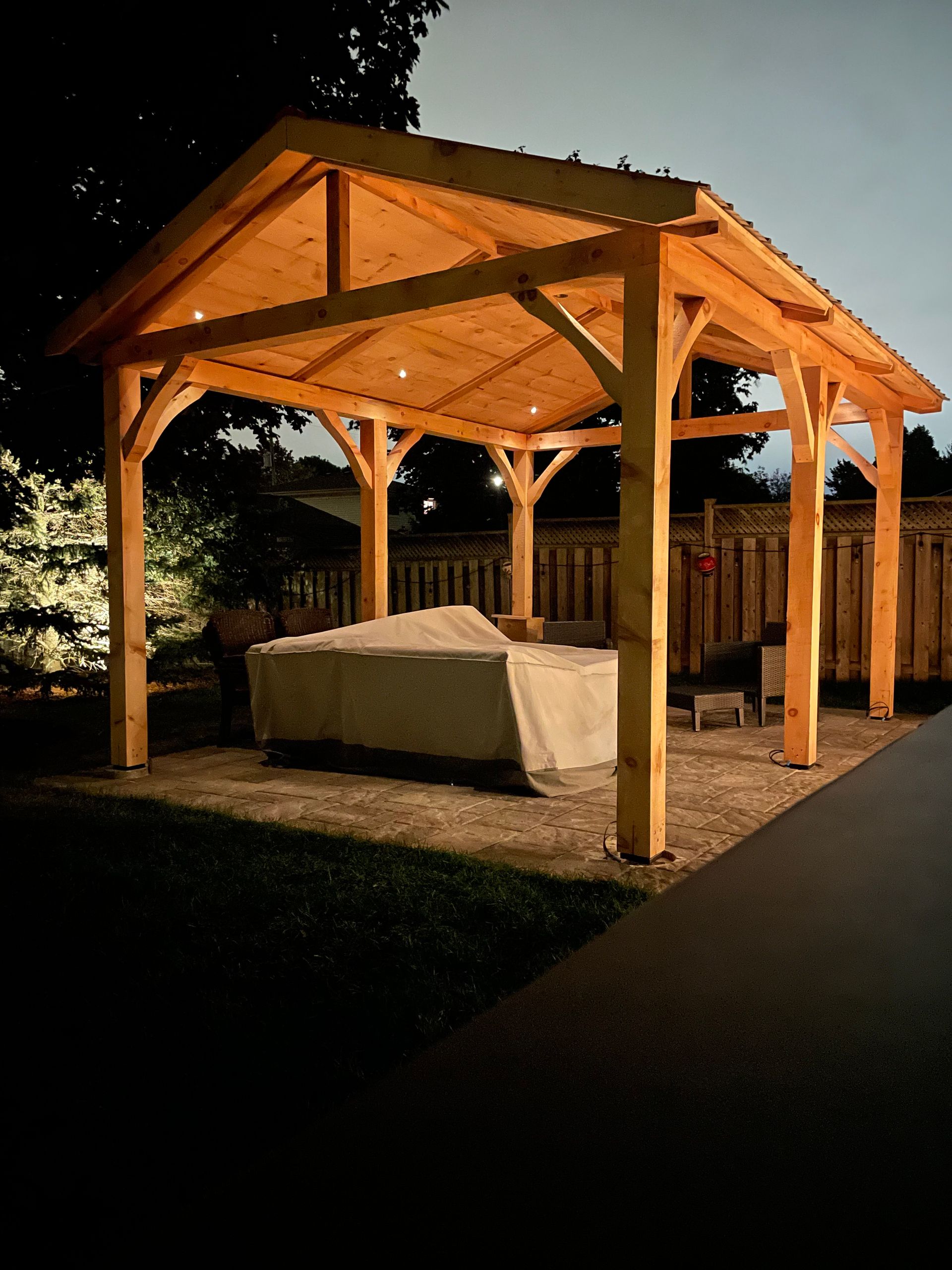 A wooden gazebo with a couch underneath it at night