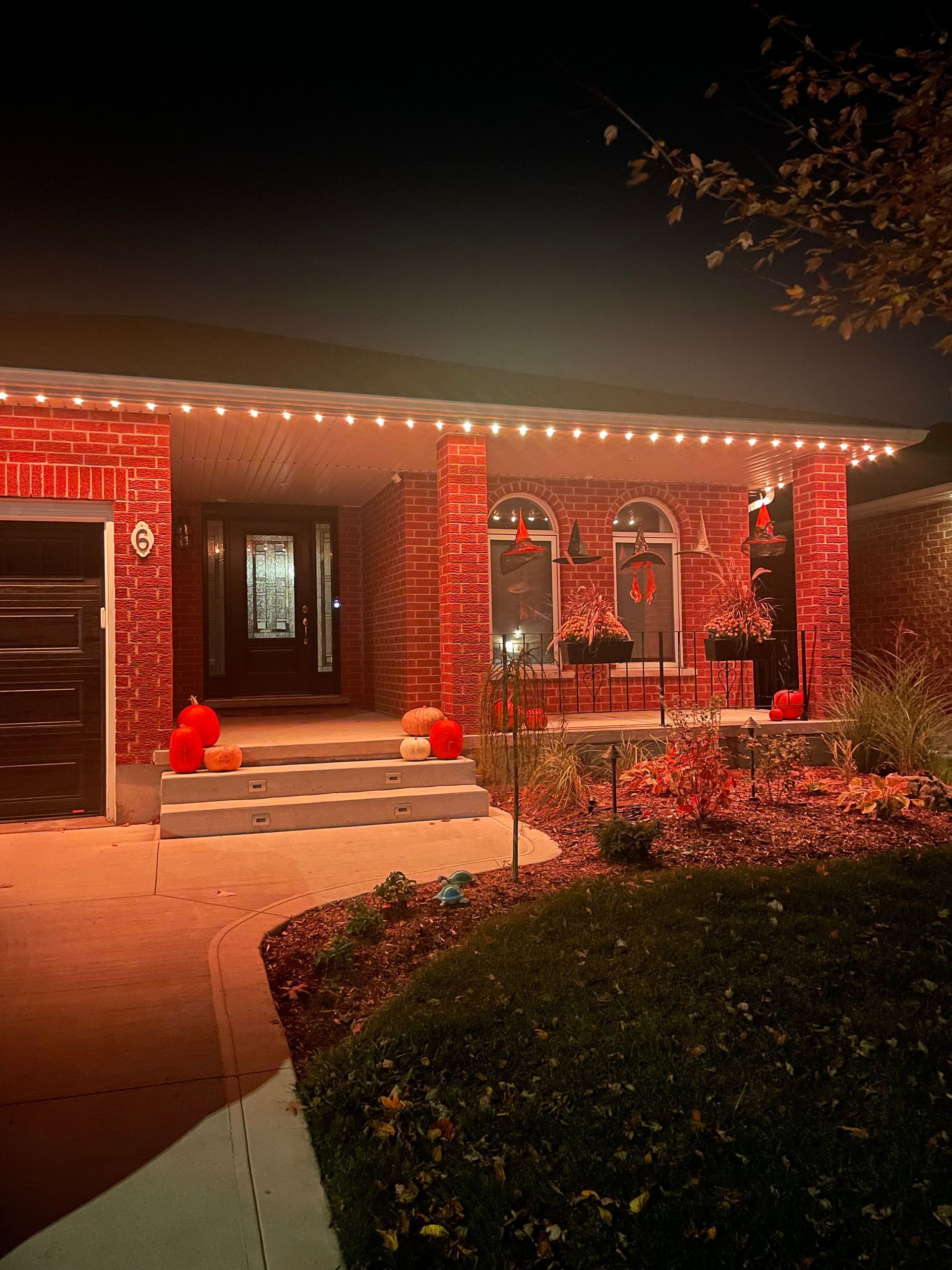 A house is decorated for halloween with pumpkins and lights.