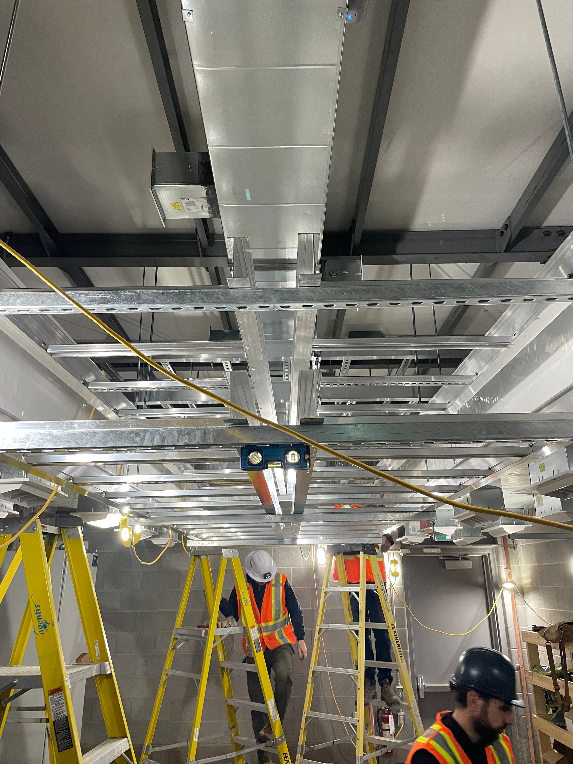 A group of construction workers are working on the ceiling of a building.