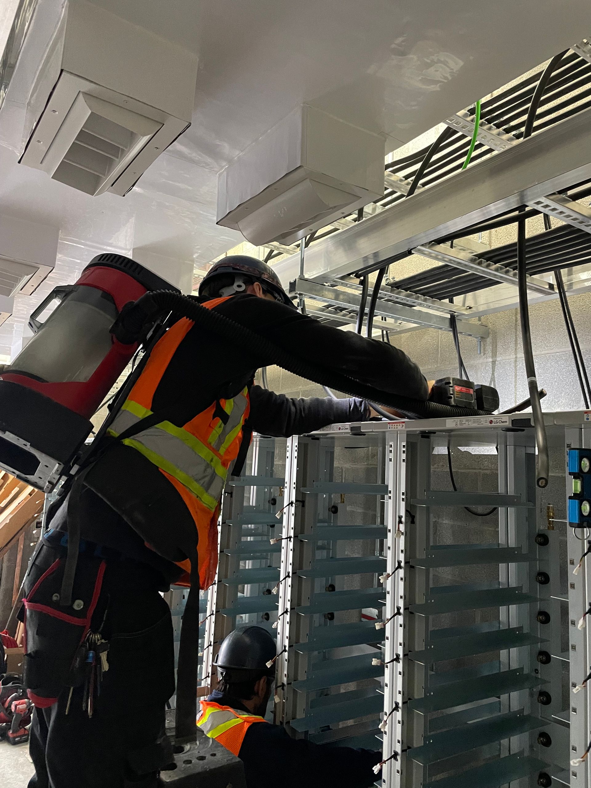 A man with a backpack is working on a machine in a room.