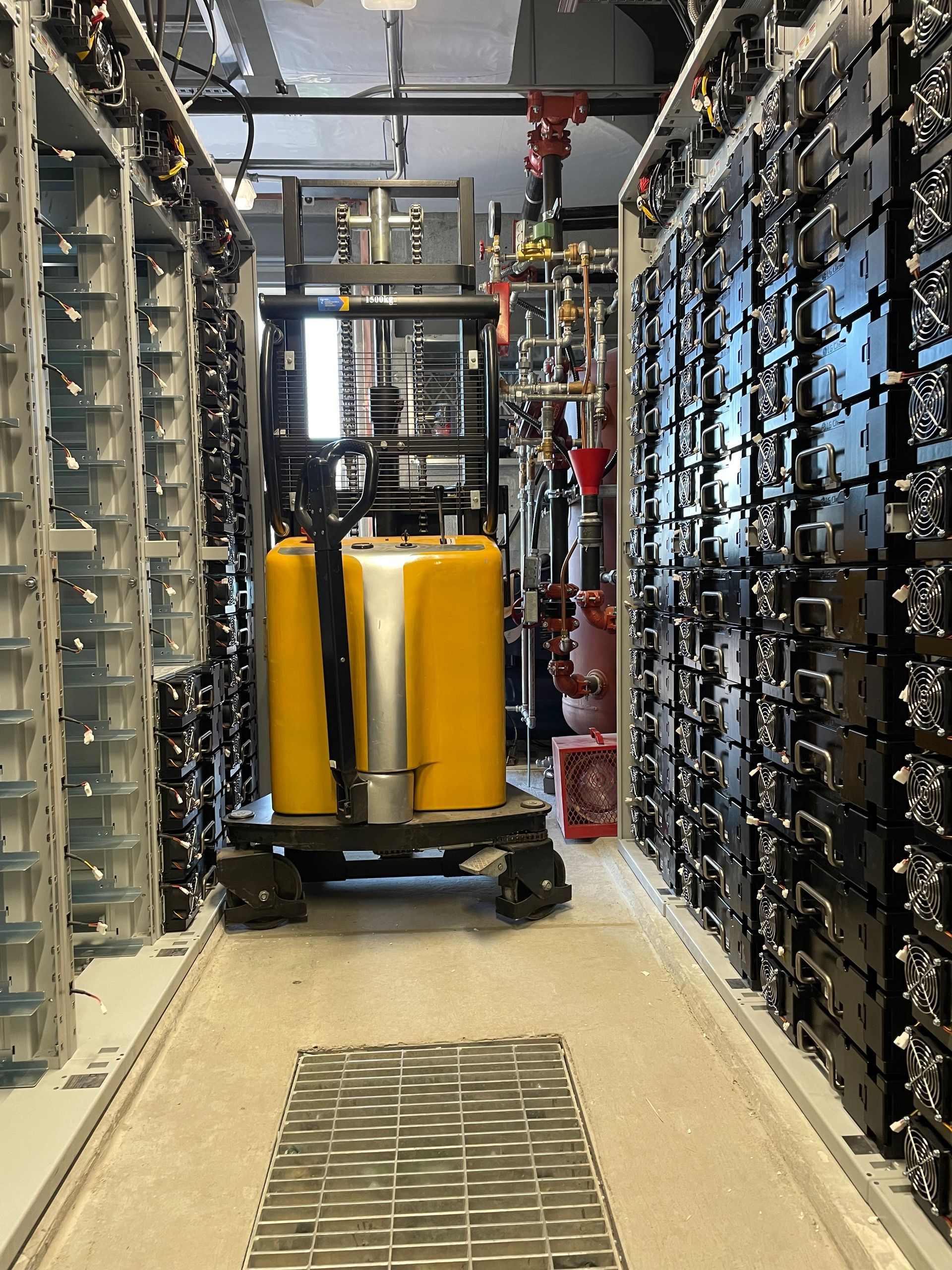 A yellow forklift is in a warehouse filled with lots of shelves