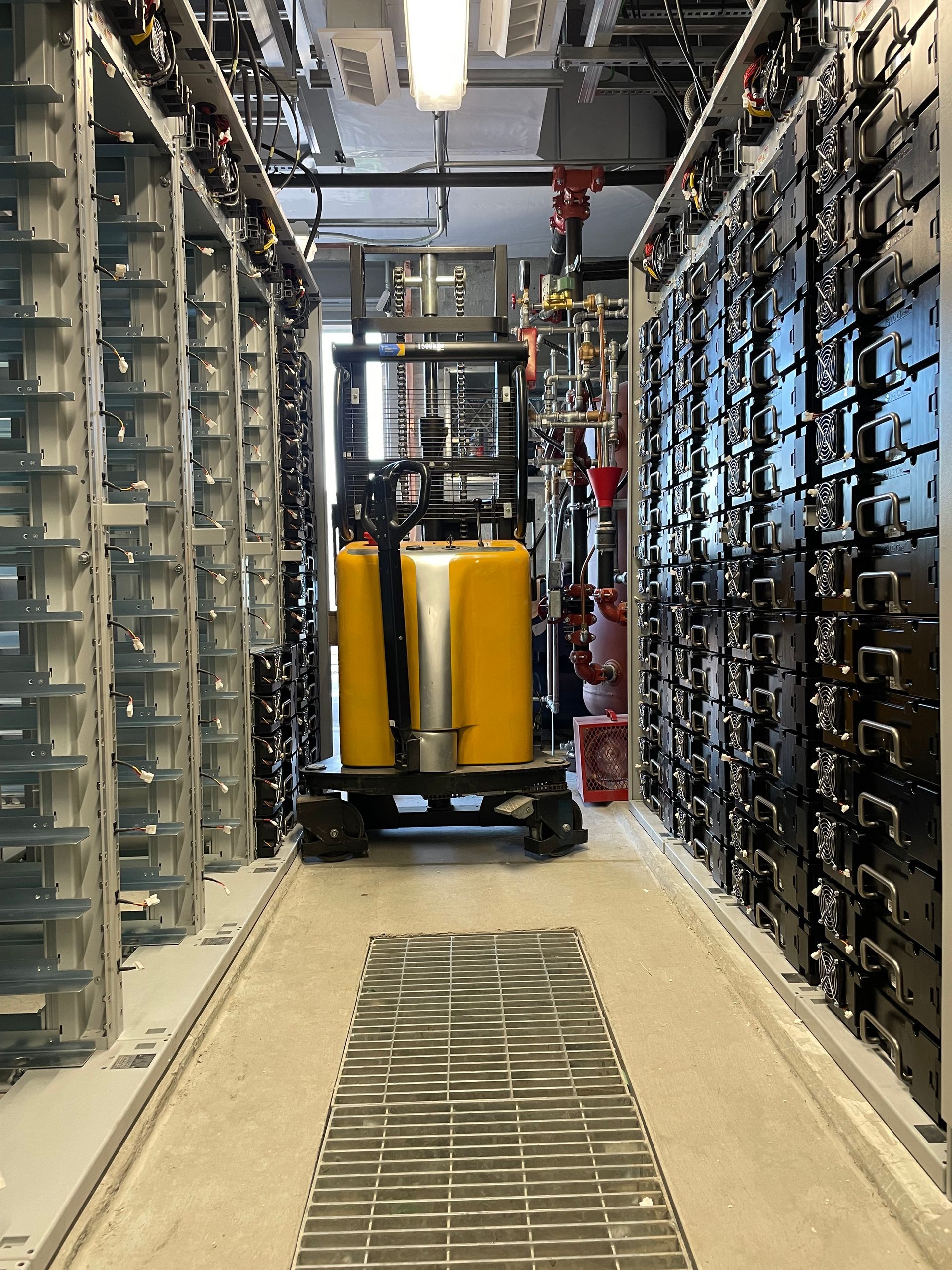 A yellow forklift is driving down a hallway in a warehouse