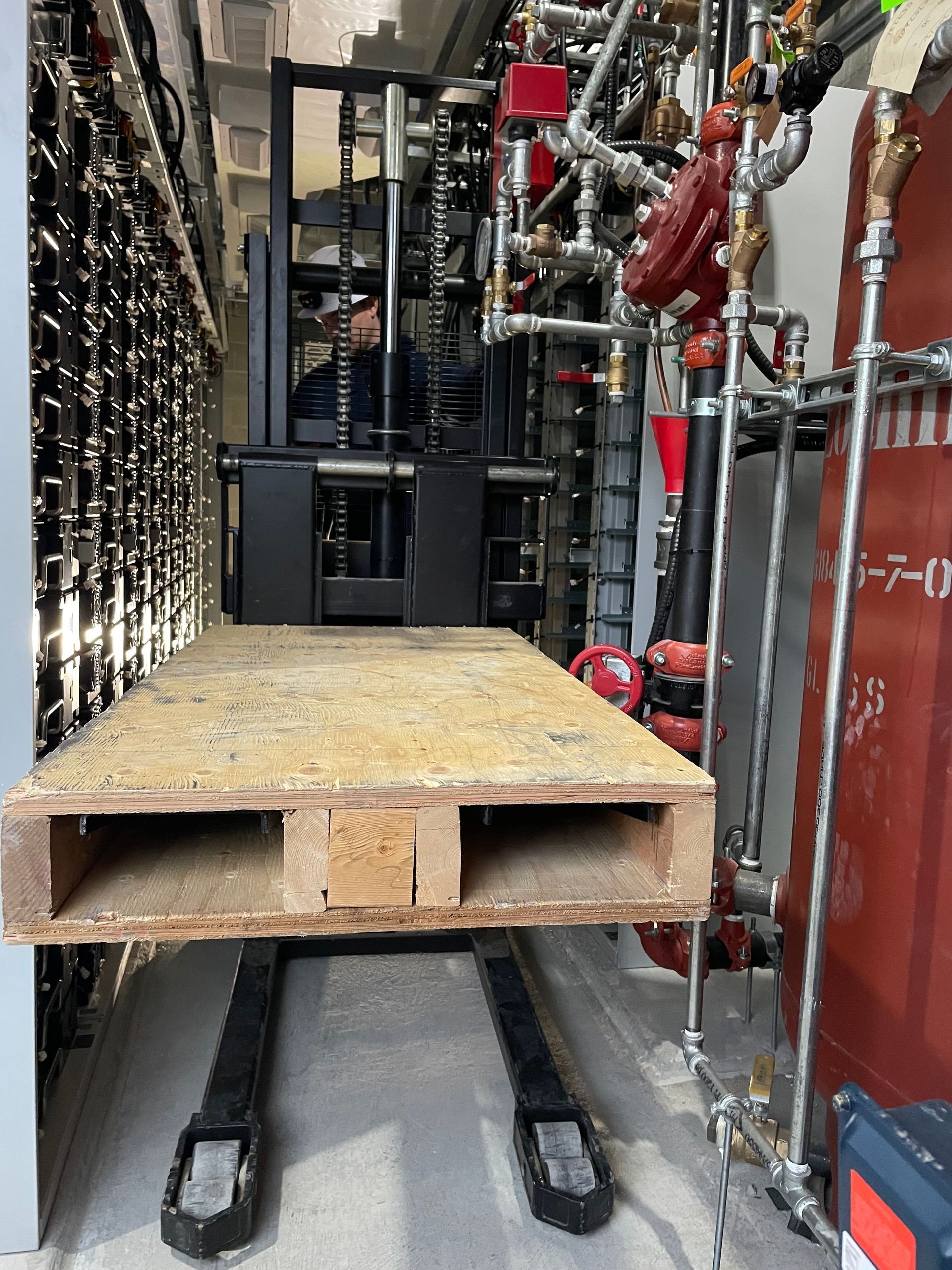A forklift is carrying a wooden pallet in a warehouse.