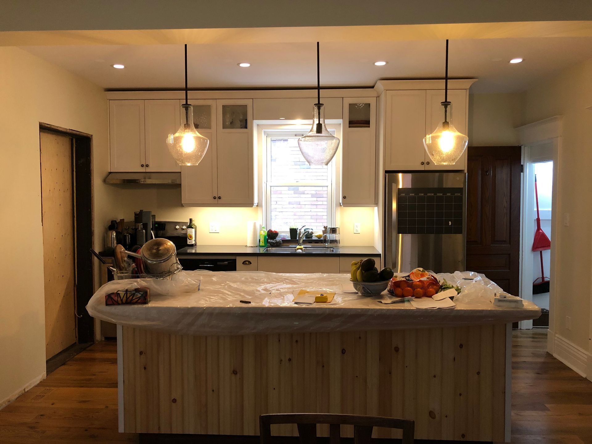 A kitchen with white cabinets , stainless steel appliances , and a large island.