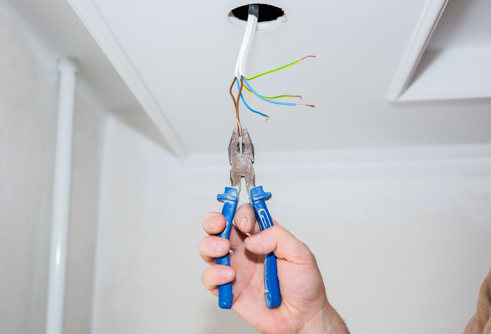 A person is cutting a wire with a pair of pliers.