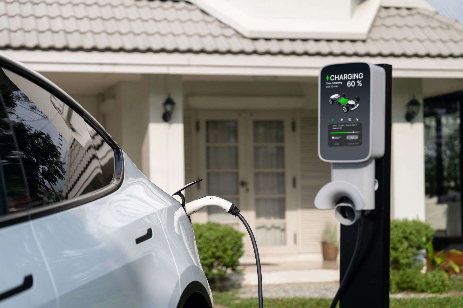 An electric car is being charged at a charging station in front of a house.