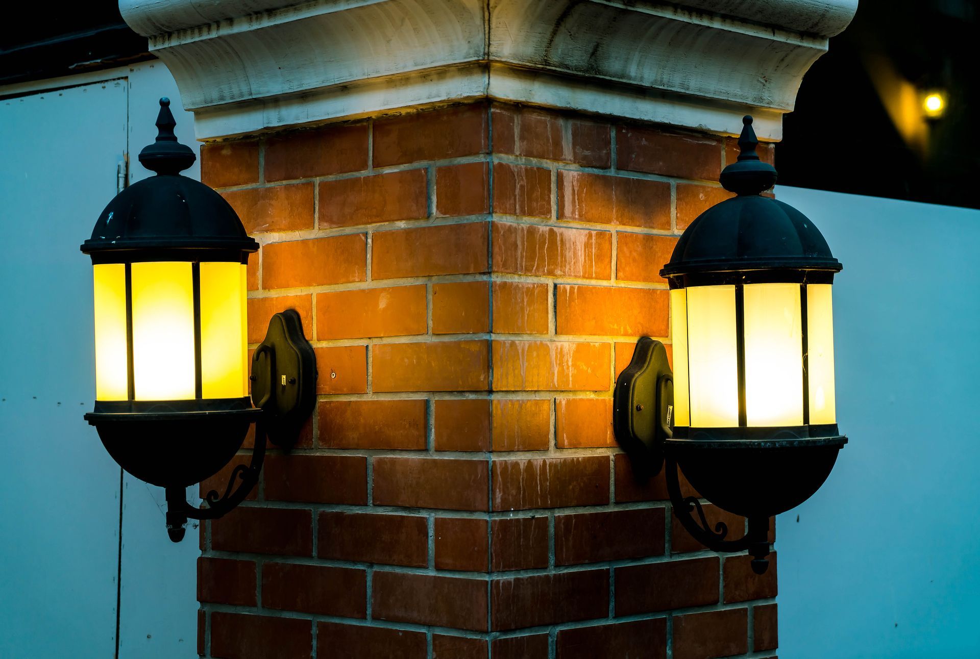 Two lanterns on a brick wall at night
