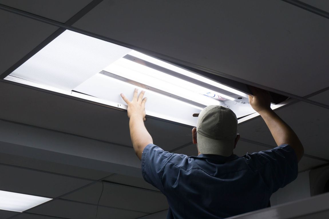 A man is fixing a light fixture on the ceiling.