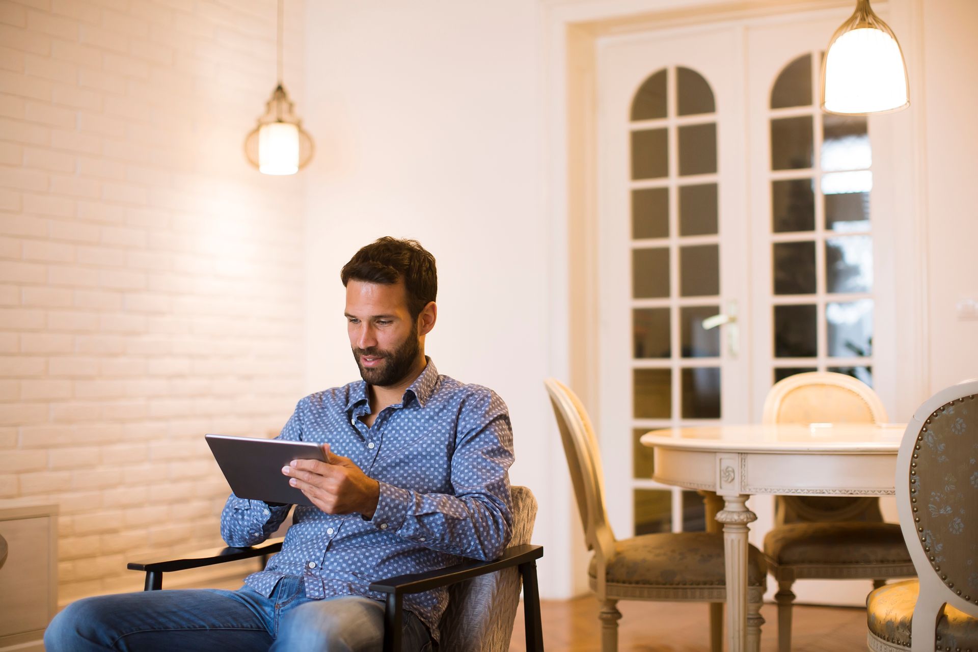 A man is sitting in a chair using a tablet computer.